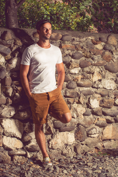 Hombre guapo parado afuera cerca de un muro de piedra
  - Foto, Imagen