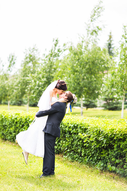 glücklicher Bräutigam hält junge schöne Braut in seinen Armen - Foto, Bild
