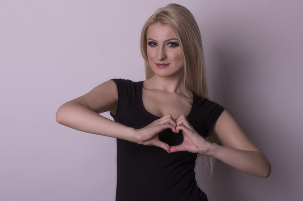 Mujer joven mostrando un corazón por los dedos
 - Foto, imagen