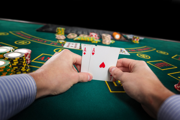 Mies pokerinpelaaja, jolla on kaksi korttia ässää
 - Valokuva, kuva