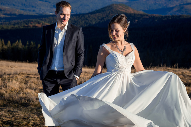 Gorgeous wedding couple posing on the mountain peak. Sunny day - Fotografie, Obrázek