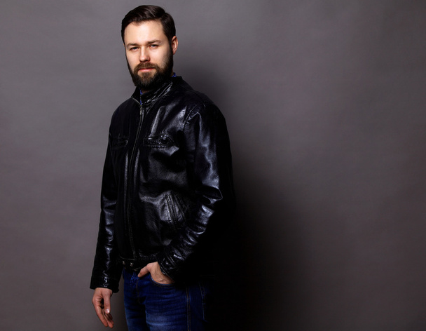 Attractive Young Man Wearing Leather Jacket on gray - Foto, afbeelding