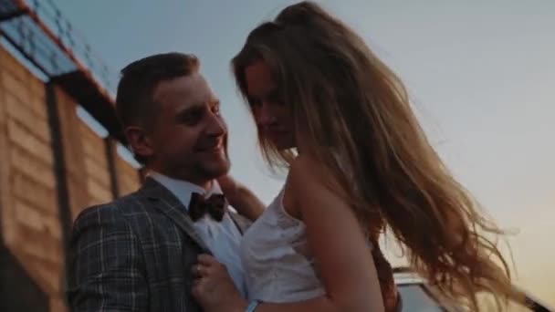 Groom holds his brides waist on a background of a dam - Materiał filmowy, wideo