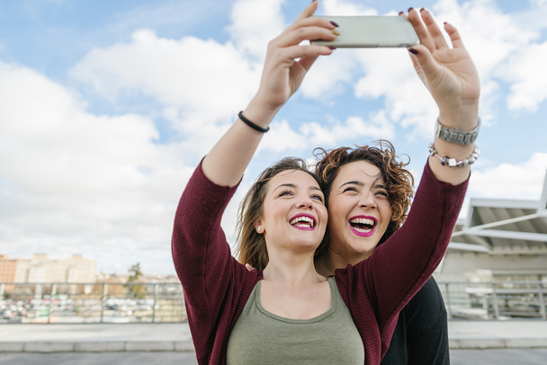 Two beautiful women taking selfiein the street. - Valokuva, kuva