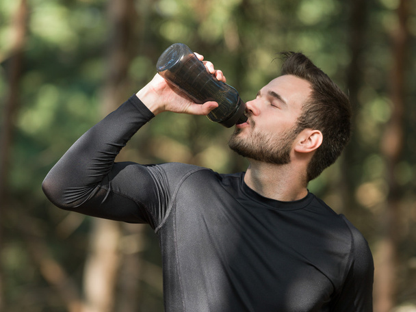 man drinking water after sport in a park - Foto, Imagem