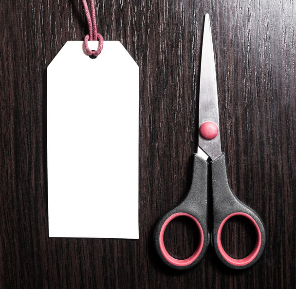 scissors lying near empty labels on brown wooden background.Blank tag. - Photo, Image