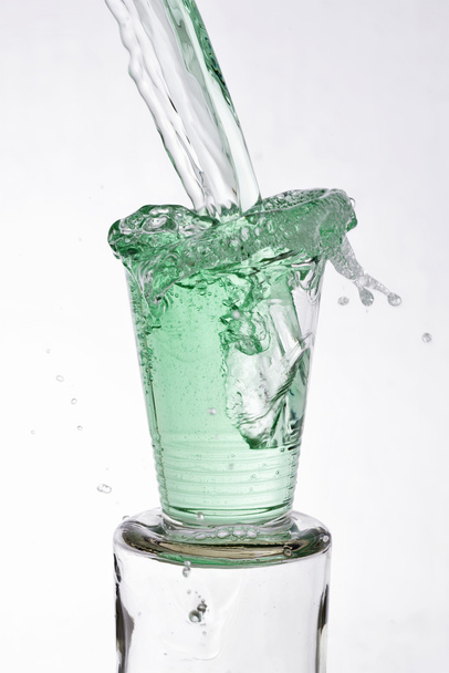 Зеленый напиток наливают в стакан
 - Фото, изображение
