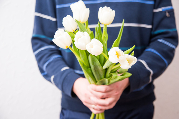 Мужчина держит букет белых тюльпанов для женщины. День матери, Во.
 - Фото, изображение