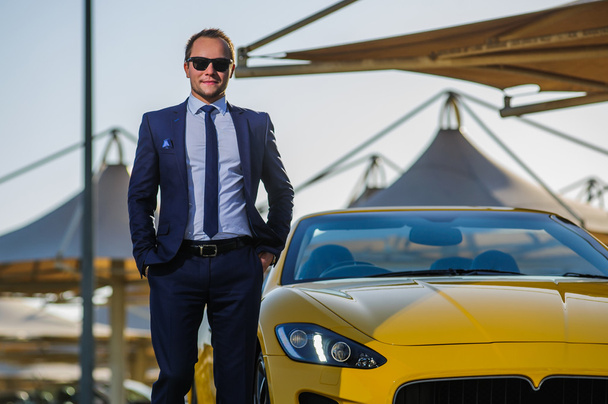 Successful yang businessman in yellow cabrio car - 写真・画像