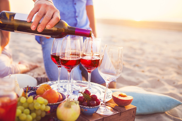 Happy friends having red wine on the beach. Sunset beach party - Foto, imagen