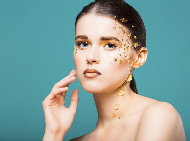Portrait of a beautiful young woman with bright golden make up - Фото, зображення