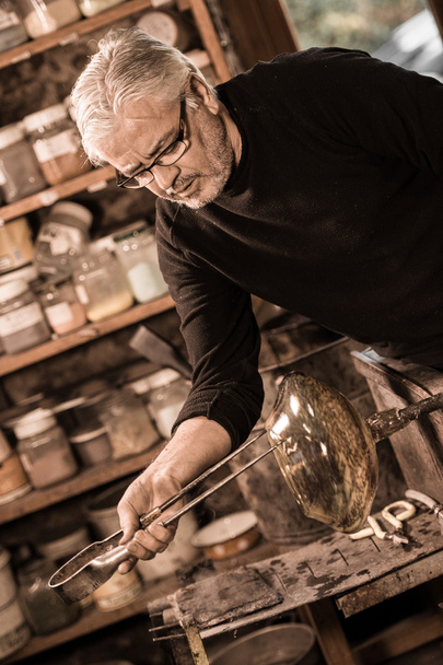 Glassblower forming molten glass in his worshop - Photo, Image