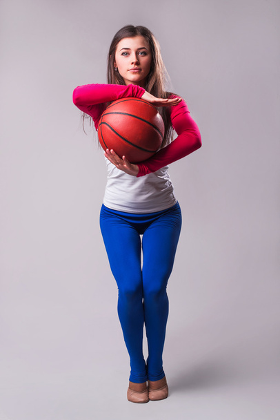 Portrét mladé ženy basketbalový hráč s míčem. Krásná Kavkazský žena v oblečení hrát basketbal na šedém pozadí   - Fotografie, Obrázek