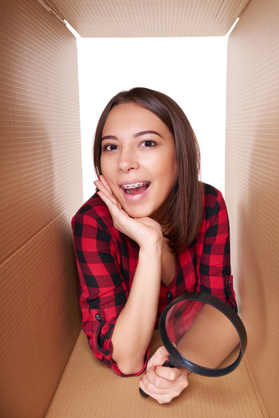 Girl opening a carton box and looking inside - Foto, imagen