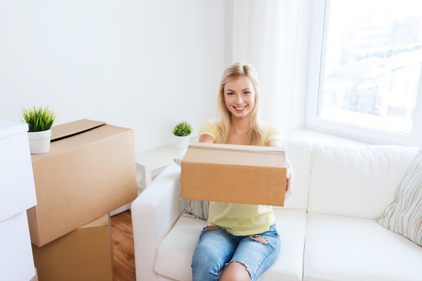 smiling young woman with cardboard box at home - 写真・画像
