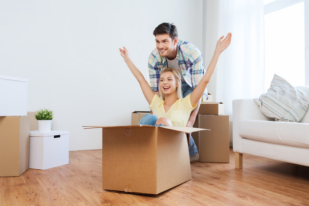 happy couple having fun with boxes at new home - Foto, imagen