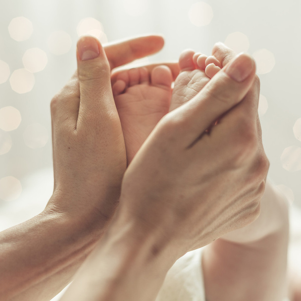 Mother touching feet of newborn - 写真・画像