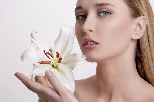 Beleza loira jovem mostrando uma flor fresca no branco
 - Foto, Imagem