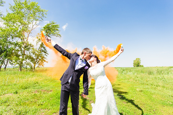 Pareja de boda besándose con humo de color en el parque de verano
 - Foto, imagen