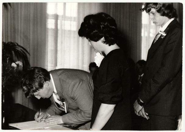 Винтажное фото показывает свидетеля свадьбы (шафера), как он делает подпись после свадебной церемонии. Черно-белое антикварное фото
. - Фото, изображение