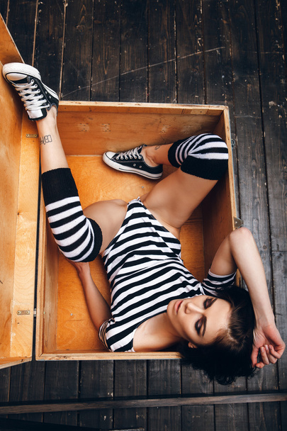 Girl in striped bodysuit in wooden box - Foto, Bild