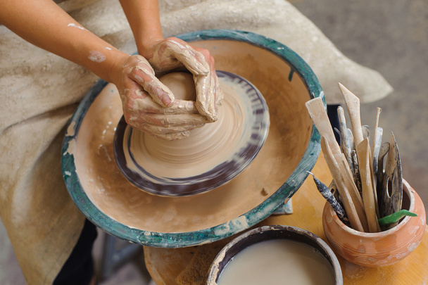 hands of a potter, creating an earthen jar on the circle - 写真・画像