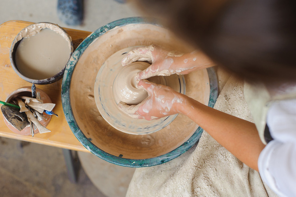 hands of a potter, creating an earthen jar on the circle - Foto, afbeelding