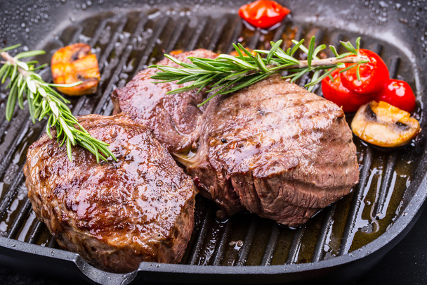 Marha steak grill. Részeket vastag marhahús lédús hátszín steak a grill teflon serpenyőben vagy régi fa tábla - Fotó, kép