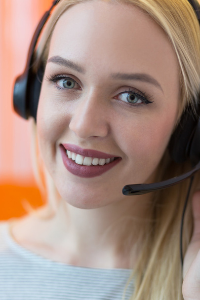 Hymyilevä nuori liiketoiminnan nainen yllään kuulokkeet vastaaminen puhelut
 - Valokuva, kuva