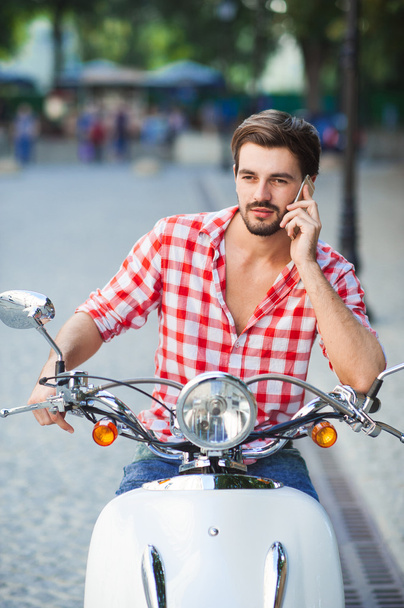 Young man on motorcycle with telephone - Photo, image