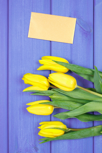 Bouquet of fresh tulips on purple wooden background, copy space for text on sheet of paper - Foto, imagen
