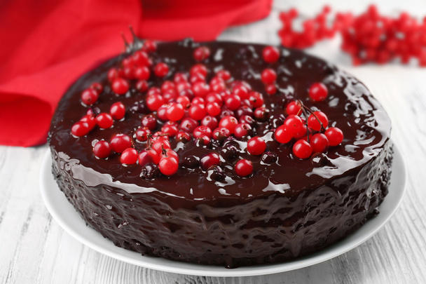 Chocolate cake with cranberries on white wooden table, closeup - Fotó, kép