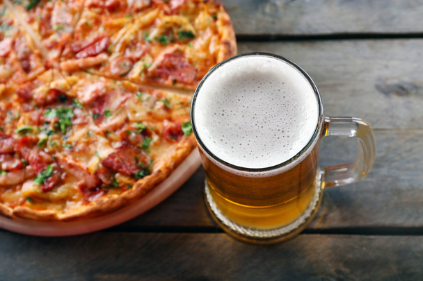 Tasty pizza and glass of beer are on wooden table, close up - Foto, immagini