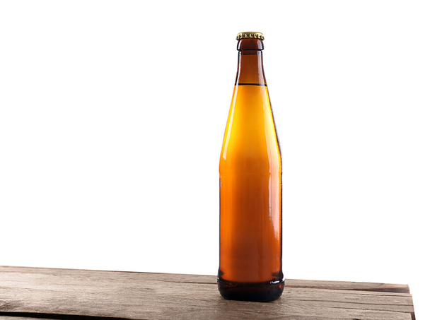 Unlabeled beer bottle on wooden table against white background - Foto, afbeelding