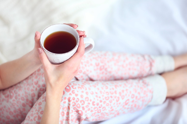 niña en un pijama sosteniendo una taza de té
 - Foto, Imagen