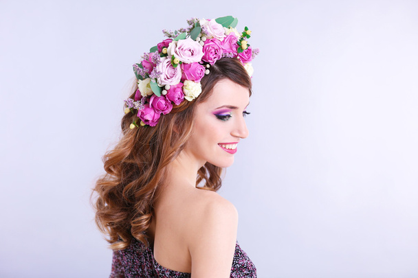 Çiçek kafa bandı gri bir arka plan üzerinde giyen güzel genç kadın - Fotoğraf, Görsel