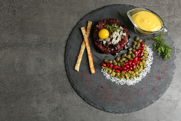Delicious beef tartare with ingredients on dark background - Fotó, kép