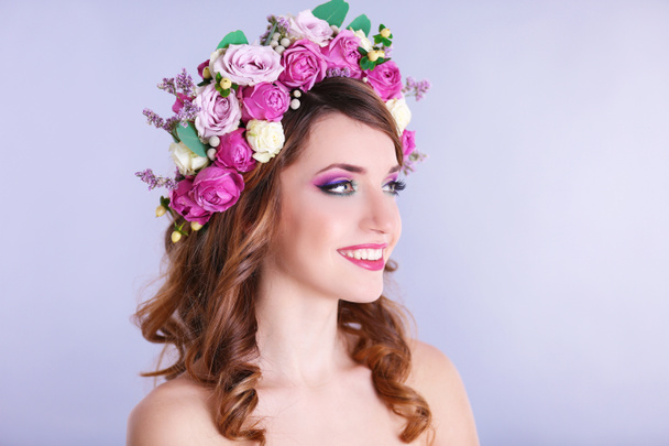 Beautiful young woman wearing floral headband on a grey background - Фото, зображення