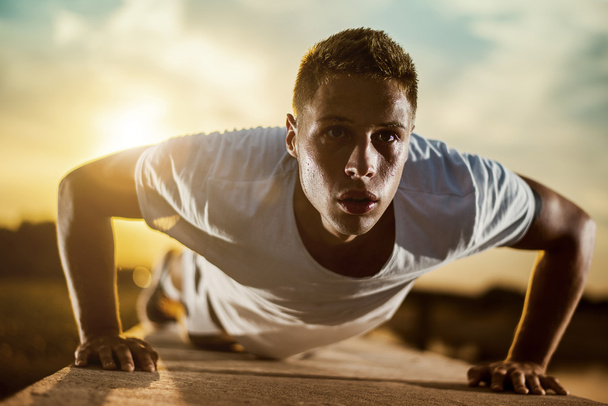Mladý atletický muž dělá kliky venku - Fotografie, Obrázek