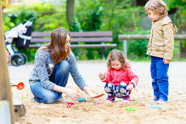 anne ve iki küçük çocuk oyun alanında oynuyor - Fotoğraf, Görsel