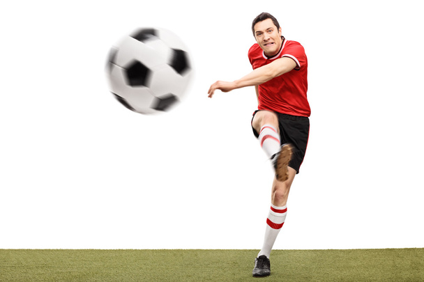 Football player kicking a ball on grass  - Foto, afbeelding