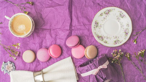 Cup of coffee with macaroons and decoration on the purple paper top view - Photo, Image