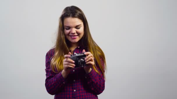junges Mädchen benutzt alte Filmkamera vor weißem Hintergrund - Filmmaterial, Video