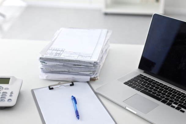 Laptop z stosem folderów na stole na białym tle - Zdjęcie, obraz