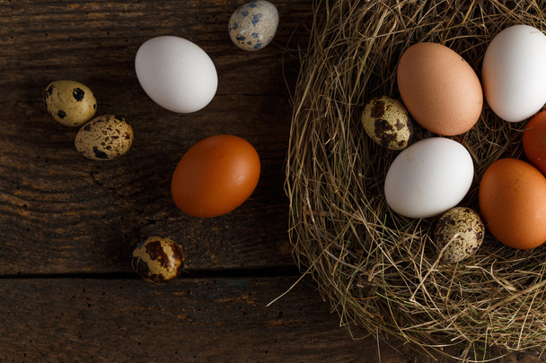 Κοτόπουλο και Ορτύκια αυγά σε μια φωλιά σε ξύλινα ρουστίκ φόντο - Φωτογραφία, εικόνα