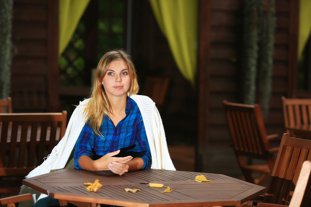 Uma rapariga sentada numa mesa de madeira. Idade 20 anos
 - Foto, Imagem