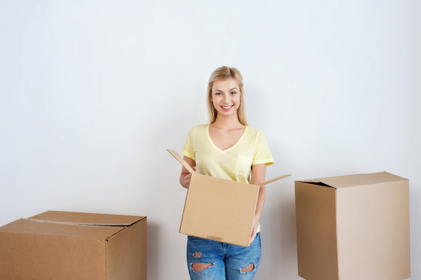 smiling young woman with cardboard box at home - Foto, Imagen