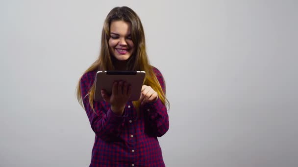 mladá dívka pomocí tabletového počítače a dělat selfie před bílou zdí - Záběry, video