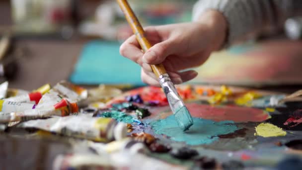 Closeup of paintbrush in woman hands mixing paints on palette - Video, Çekim