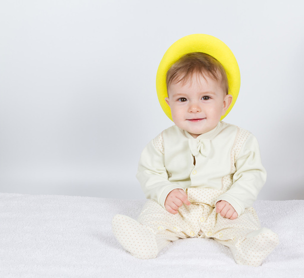 Vauva keltaisessa hatussa istuu.
 . - Valokuva, kuva